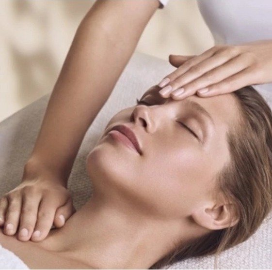 Praticienne prodiguant un soin visage hydratant et un massage la chaud de fonds.